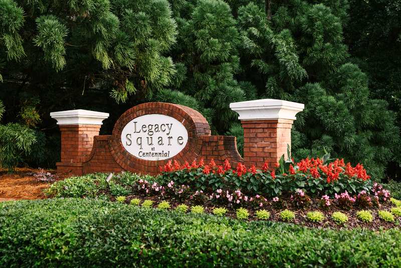 Brick neighborhood entrance sign with landscaped flowers and greenery in Metro Atlanta