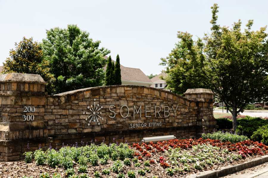 Somerby Senior Living entrance sign with stone wall and flowers in Metro Atlanta